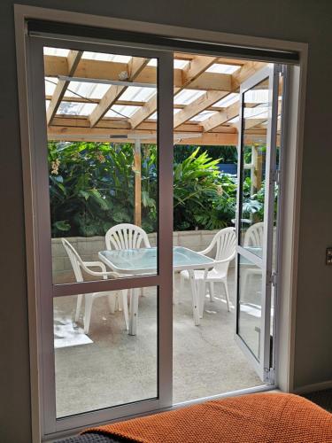 a glass door leading to a patio with a table and chairs at Little Hill on Sycamore in New Plymouth