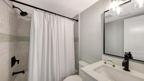 a bathroom with a white shower curtain and a sink at Canal 313 - Right in Siesta Key Village! in Siesta Key
