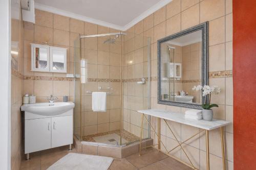 a bathroom with a sink and a shower with a mirror at Lodge At The Link in Kempton Park