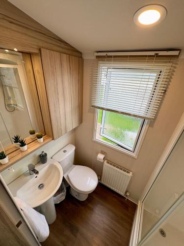 a bathroom with a toilet and a sink and a window at Chesil View in Wyke Regis