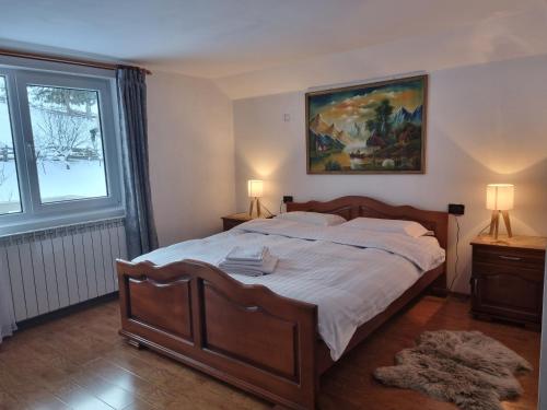 a bedroom with a large bed and a painting on the wall at Pensiunea Casa Bradet in Statjunea Borsa