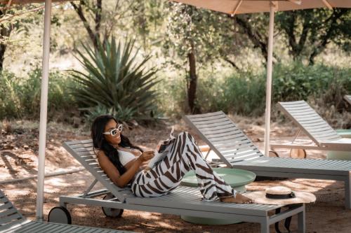 a woman sitting on a lounge chair on a patio at Thaba eNtle Private Boutique Game Farm in Thabazimbi