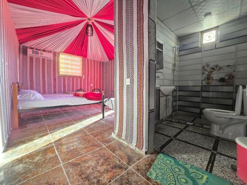 a pink room with a bed and a toilet at Scarlet Luxury Camp Wadi Rum in Wadi Rum