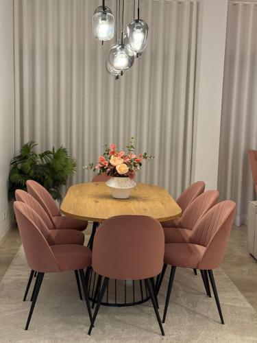 a dining room table with pink chairs and a vase of flowers at Odivelas Place 1 in Odivelas