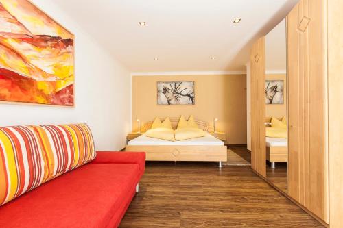 ein Schlafzimmer mit einem Bett und einem roten Sofa in der Unterkunft Art-Apartments Kartnaller superior in Neustift im Stubaital