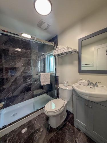 a bathroom with a toilet and a sink and a shower at Sunrise Motel in Owen Sound