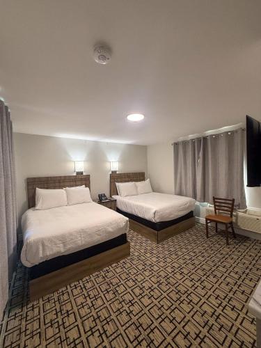 a hotel room with two beds and a flat screen tv at Sunrise Motel in Owen Sound