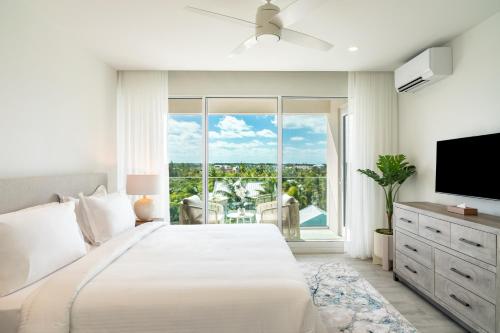 a white bedroom with a large bed and a large window at Ellipse Resort, Grace Bay in Providenciales
