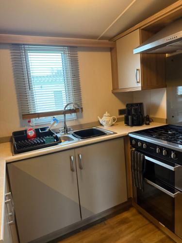 a kitchen with a sink and a stove at Serenity 2 and Serenity 1 Central lounge sleeps 6 3 bedrooms with 2 bathroom in Carlton Colville