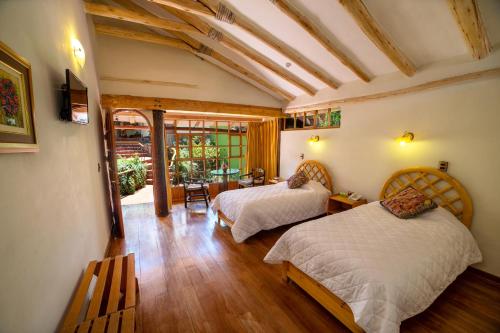a bedroom with two beds and a table and chairs at IORANA HOTEL Urubamba in Urubamba