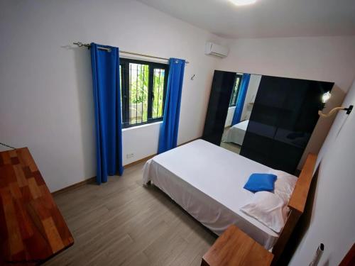 a bedroom with a bed and a window with blue curtains at Label résidence 2 in Grand-Baie