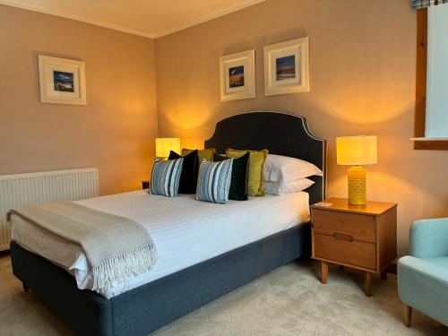 a bedroom with a large bed and a blue chair at Pabbay House in Back