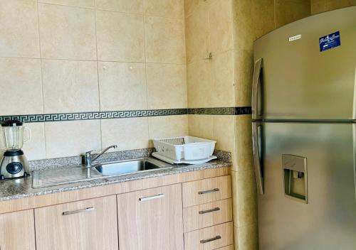 a kitchen with a sink and a refrigerator at Amplia suite cerca a La Carolina - Av 6 Diciembre in Quito