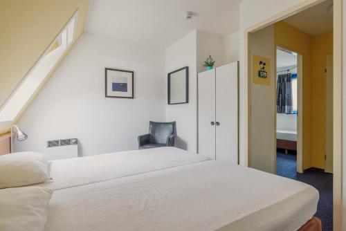a bedroom with a large white bed and a staircase at Hollumerstrand in Hollum