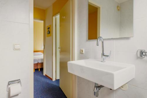 a bathroom with a white sink and a bedroom at Hollumerstrand in Hollum