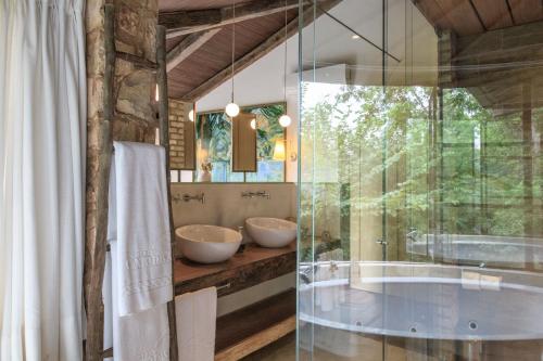 a bathroom with two sinks and a tub at Hotel Canto das Águas - Roteiro de Charme in Lençóis