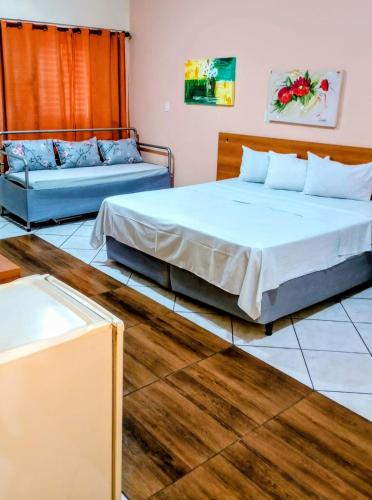 two beds and a couch in a room at Calabreza Hotel e Restaurante in Três Corações