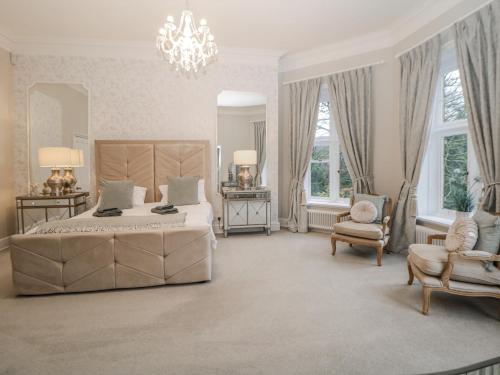 a bedroom with a bed and two chairs and a chandelier at Hallfield Hall in Alfreton