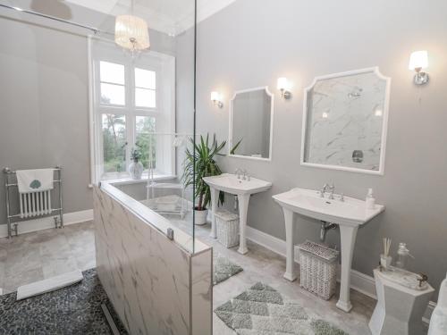 a bathroom with two sinks and a tub and a mirror at Hallfield Hall in Alfreton