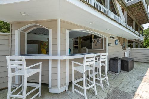 a patio with a bar with stools in front of a house at Beach Cabana - Southern Shores, 6 En-Suites, Elevator, Pool, Cabana Bar, Hot Tub, Game Room in Southern Shores