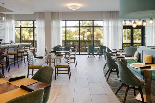 a dining room with tables and chairs and windows at EVEN Hotel Miami - Airport by IHG in Miami