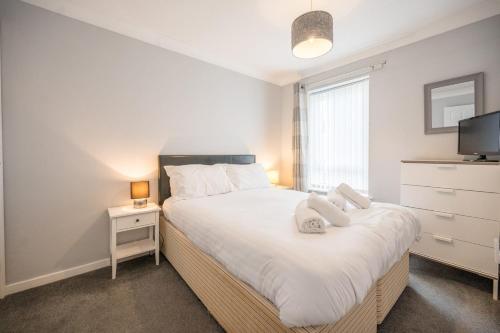 a bedroom with a bed with white sheets and a tv at 100 Waterside Park in Corton