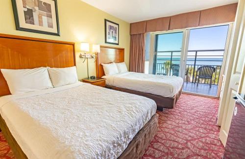a hotel room with two beds and a balcony at Oceanfront Convenience on Lower Floor, Heated Pool in Myrtle Beach