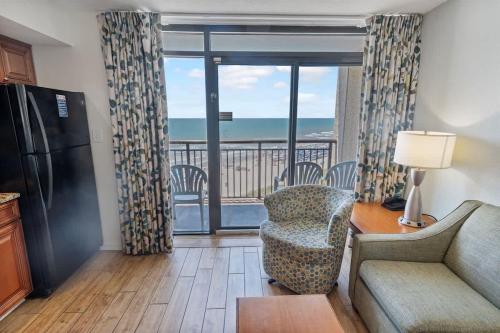 a living room with a couch a chair and a refrigerator at New Remodeled Direct Oceanfront Views Beach Cove in Myrtle Beach