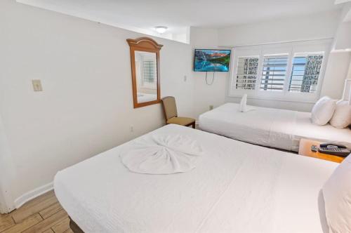 a white bedroom with two beds and a mirror at New Remodeled Direct Oceanfront Views Beach Cove in Myrtle Beach