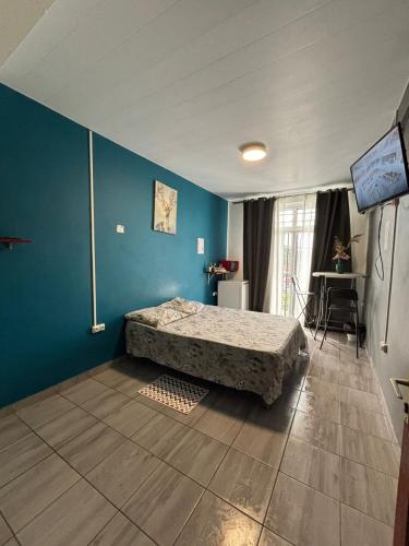 a bedroom with a bed and a blue wall at Cayenne Centre Eco Castor in Cayenne