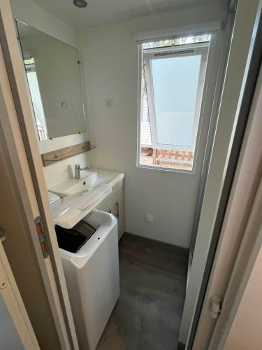a white bathroom with a sink and a window at La Carabasse camping siblu in Vias