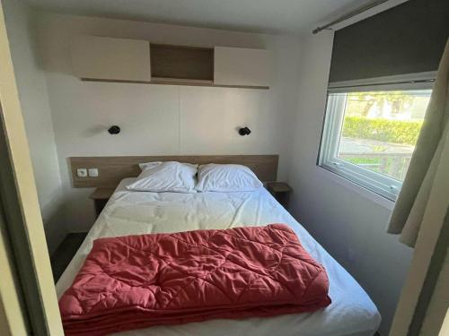 a bedroom with a bed with a red blanket on it at La Carabasse camping siblu in Vias
