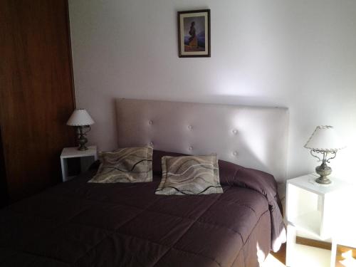 Un dormitorio con una cama con dos mesitas de noche y dos lámparas. en Manilo House, en Mar del Plata