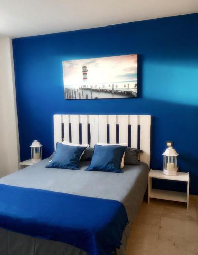 a blue bedroom with a bed with a blue wall at On the beach in Corralejo