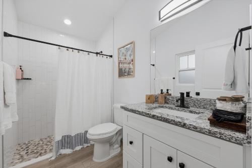 a white bathroom with a toilet and a sink at Cozy Coastal Cottage Minutes to Beach and Downtown in St. Augustine