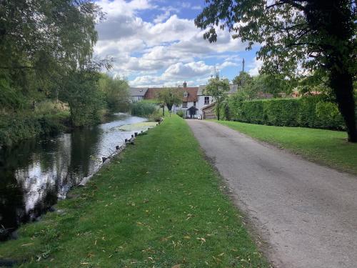 a dirt road next to a river with houses at Bellows Mill in Dunstable