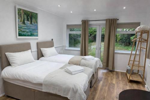 two beds in a room with windows and a ladder at Stansted Stop Over in Takeley