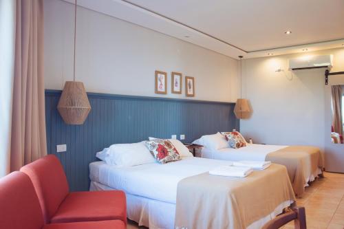 a hotel room with two beds and a chair at Tramonto hotel & ristorante in Empedrado