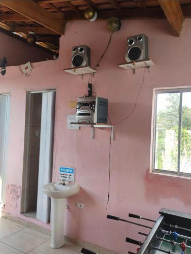 a room with a pink wall with a sink and speakers at Casa com piscina in Mairiporã
