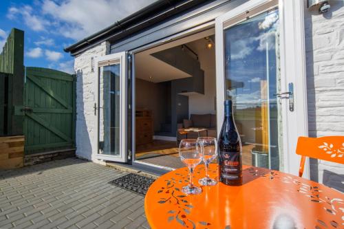 a table with two wine glasses and a bottle on it at Little Cottage of the Beacons in Brecon