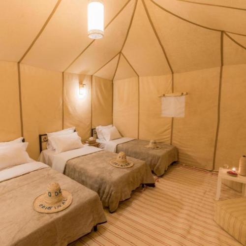 a room with three beds in a tent at Sunny Luxury Camp in Merzouga