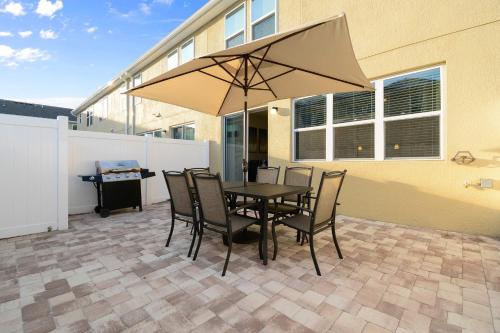 a table and chairs with an umbrella on a patio at Four Bedrooms Resort TownHome 5128 in Kissimmee