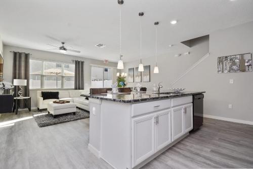 a kitchen with white cabinets and a living room at Four Bedrooms Resort TownHome 5128 in Kissimmee