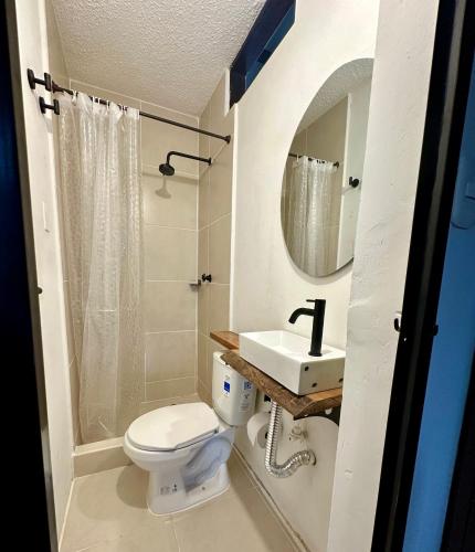 a bathroom with a toilet and a sink and a mirror at Finca Hotel Buenos Aires in Guamal