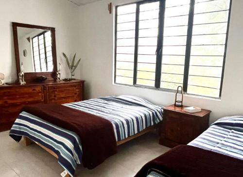 a bedroom with two beds and a dresser and a mirror at La Enamorada Cabañas & Resort in Zacatlán