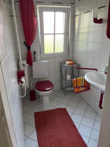 a bathroom with a red toilet and a sink at Doppelzimmer mit Gartenblick in Reckershausen