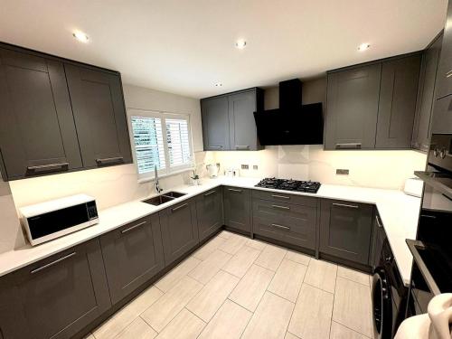 a kitchen with black cabinets and a white floor at Luxury home Cheshunt in Wormley