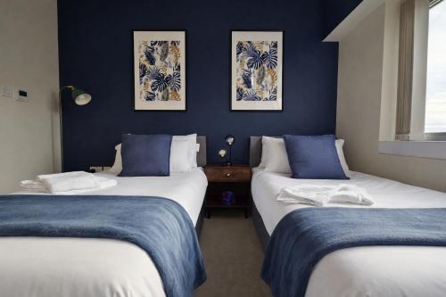 two beds in a room with blue walls at 2 Bed Flat - Contractor - Central MK - Parking - Sleeps5 in Milton Keynes