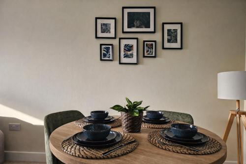 a dining room table with bowls and plates on it at 2 Bed Flat - Contractor - Central MK - Parking - Sleeps5 in Milton Keynes