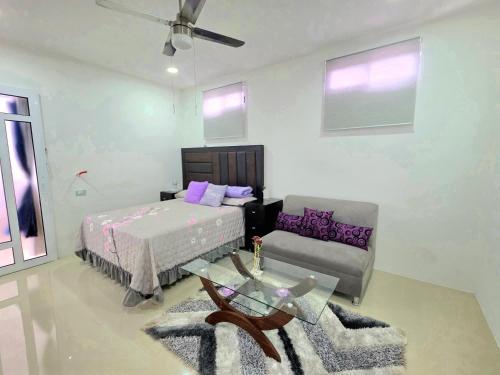 a bedroom with a bed and a couch and a table at Sweethome Mérida in Mérida